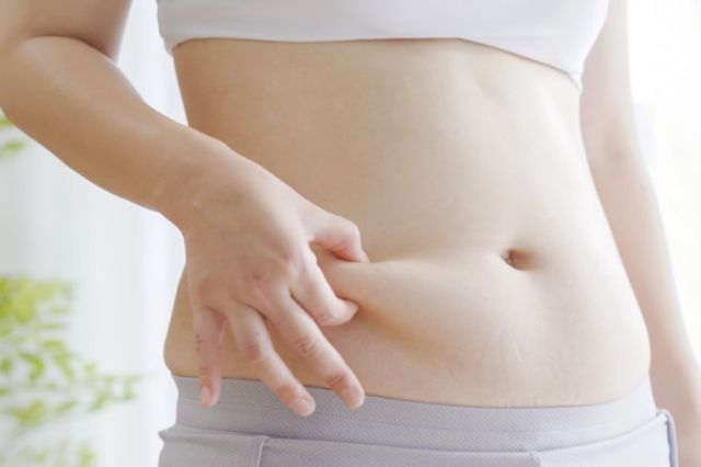 お腹をつまむ女性