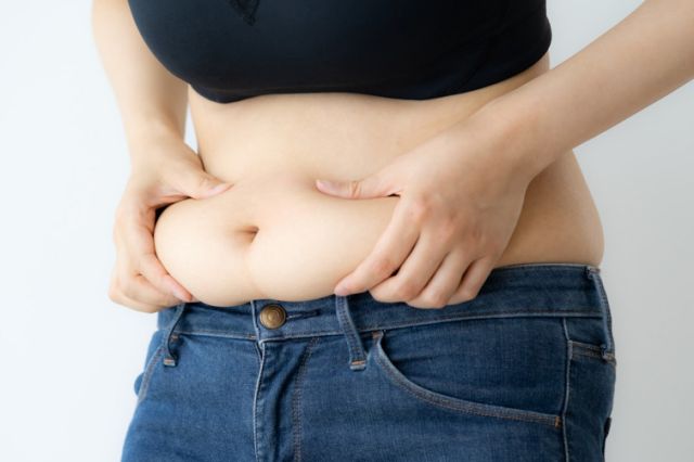 お腹をつまむ女性